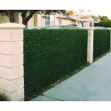 Haie artificielle Lux-2R verte installée sur une clôture de jardin entre deux piliers en béton
