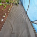 Toile de paillage noire 130g/m² installée dans une serre pour limiter la pousse des mauvaises herbes entre les rangs de culture