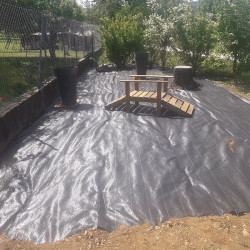 Toile de paillage noire 130g/m² installée dans un jardin pour un aménagement propre, prête à accueillir du paillis ou des planta