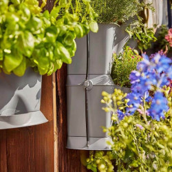 Gros plan sur les jardinières verticales NatureUp! avec tuyau micro-drip fixé au centre, arrosant discrètement les plantes.