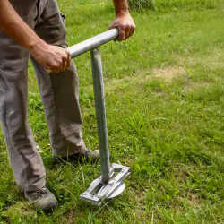 Utilisation d'une clé à visser pour enfoncer une épée à vrille dans le sol d’un jardin
