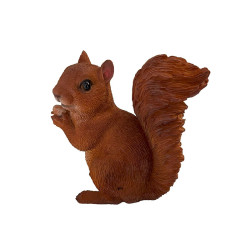 Vue latérale gauche de la figurine d’un écureuil brun, assis, tenant une noisette dans ses pattes avant.
