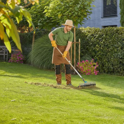 jardinier qui passe le scarificateur dans une pelouse