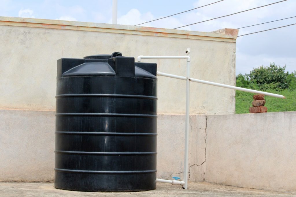 Protéger son potager avec un bidon noir posé sur un toit afin de stocker l'eau de pluie