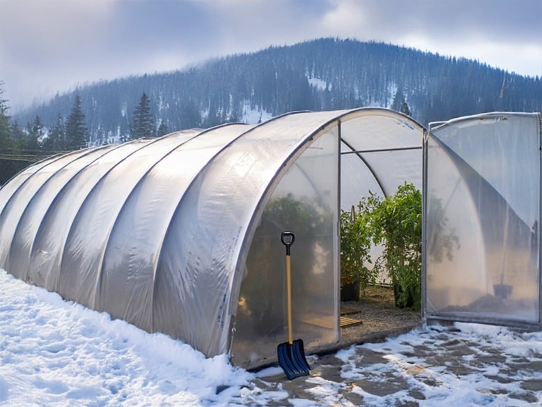 Serre tunnel eco avec neige et rateau dans un paysage montagneux